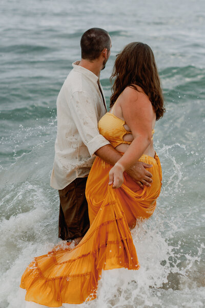 A couple embraces in the waves during their coastal inspired engagement session