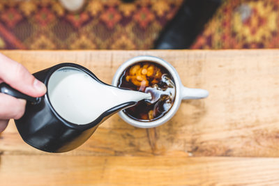 Cream being poured into a cup of coffee