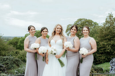 Bridesmaids and bride holding bouquets  in a garden by Scotland wedding photographer
