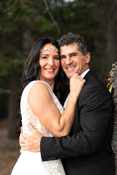 Bride and groom face to face looking at camera smiling.