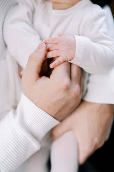 Close-up of baby hand holding adult finger, intimate moment captured by Toronto-based family photographer