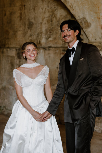 A newlywed couple holding hands and smiling together 