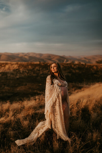 Pregnant mother facing the setting sun in a boho dress.