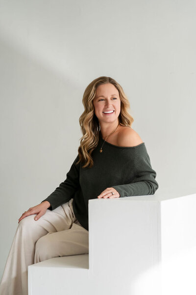 Branding coach Kaitlyn David holding notebook, smiling, and working from a cozy chair