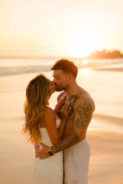 attractive couple kiss on the beach in makena during their wailea enagement photoshoot with love and water