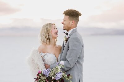 A bride and groom laugh together at sunset while at the Bonneville Salt Flats on their wedding day.