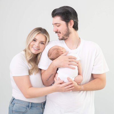 Beautiful new mom and dad with baby in a studio portrait