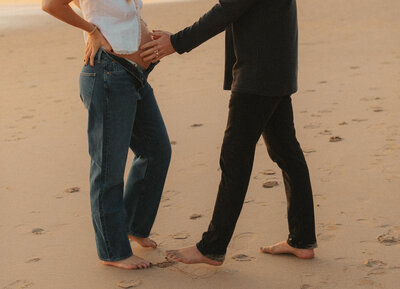 a husband putting his hands gently on his wife's pregnant belly