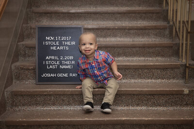 little boy all messy at his one year photoshoot with blue and white balloons