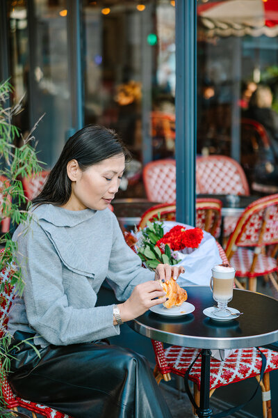 Stylish solo woman in a leather jacket and jeans, smiling confidently during a Paris photoshoot near the Louvre and Pont des Arts.