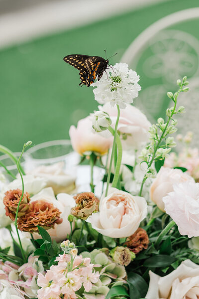 A couple that just got married at an altar surrounded by colorful flowers, the groom is behind the bride, and in the background its the Château Bouffémont