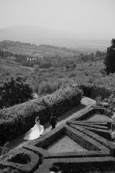 A wedding couple walking through an intricate garden 