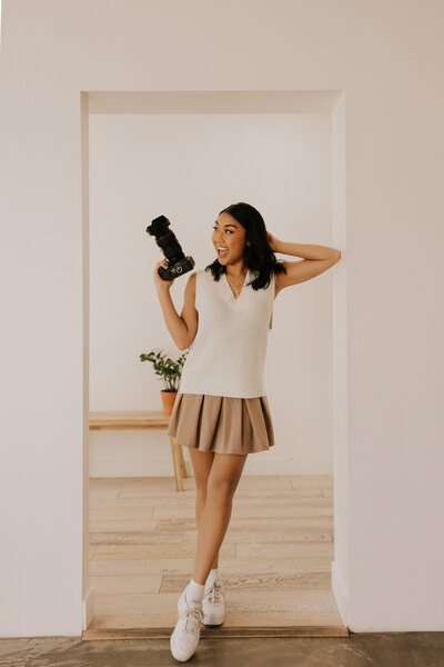 woman leaning against doorframe while holding camera