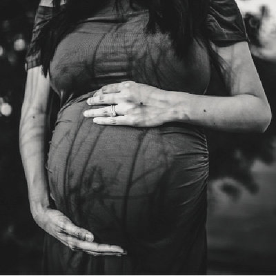 Artistic maternity close up of belly with shadow reflections in black and white.