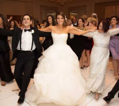 Bride in a strapless gown dancing with guests in a lively wedding reception circle dance
