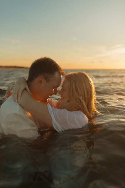 couple embrace in ocean for lifestyle photos at pei