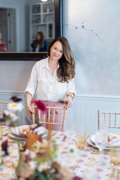 top uk wedding planner emma westacott standing at an event dining table positioning a chair to complete the event design