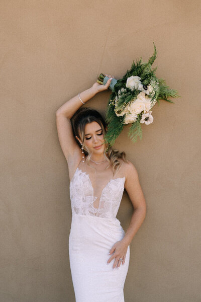 bride holding bouquet up against wall by wedding videographer tampa