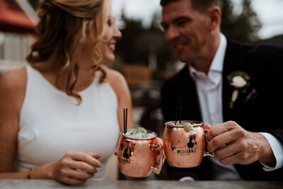 Couple toasts with Breckenridge Distillery mugs during their wedding celebration in Colorado.