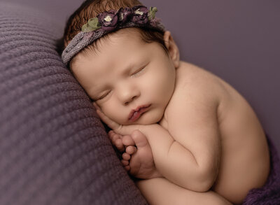 newborn baby sleeping on a purple textured blanket