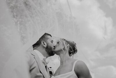 black and white image under the veil as bride and groom exchange a kiss, Kimberly Dean Photos Baltimore and DMV wedding Photography