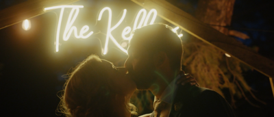 bride and groom kissing in front of neon sign