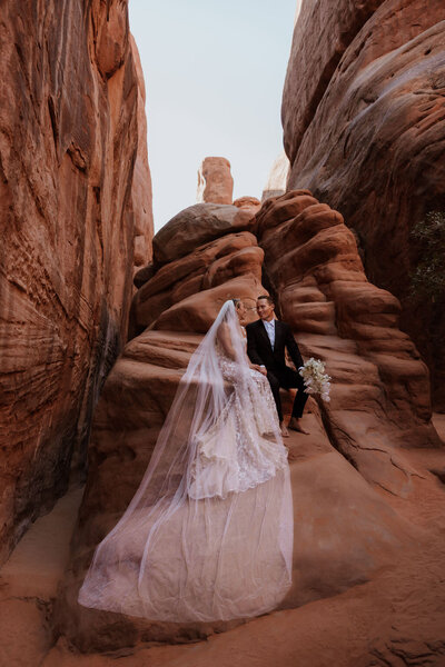 bride and groom standing in the desert surrounded by rock walls