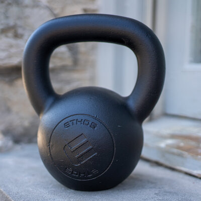 a kettlebell, tool used in online strength training programs, sits on a windowsill