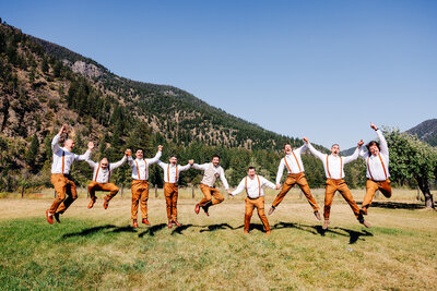 Groom and groomsmen jumping at Blackfoot River House wedding venue in Bonner, MT