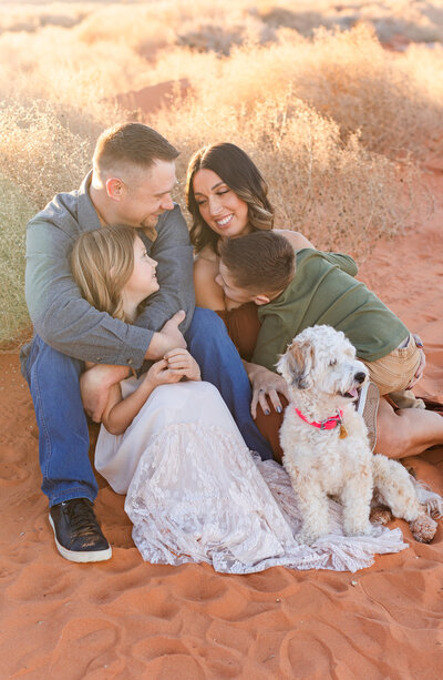 family sitting in the sand at sand hollow state park for family photos
