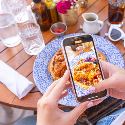 Love Social Media team member taking a photo of a waffle on a pretty plate for a social media client's Instagram