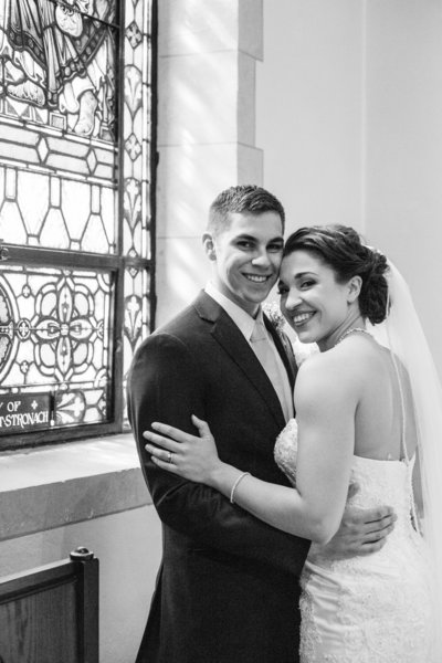 couple stand by stained glass after ceremony