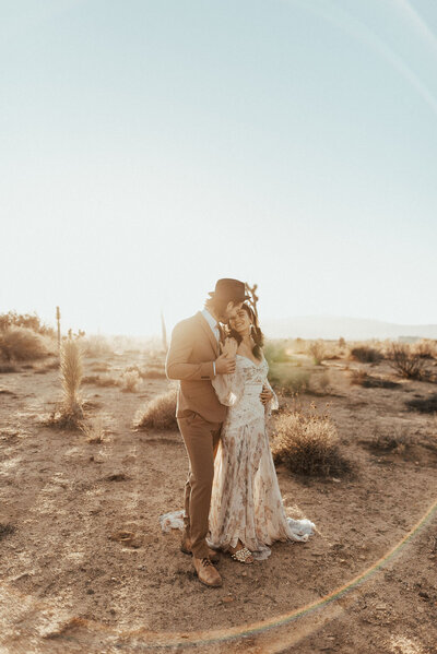 Bride and groom standing next to each other in the desert