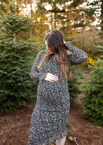 Mom to be touching belly in forest by Portland maternity photographer
