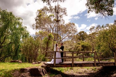 Close up of a pregnant belly with the mother wearing a brown jumper and jeans while leaning against a white weatherboard wall