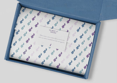 Maquette de présentation de l'identité visuelle de Delisa Buffet, qui représente le packaging d'un carton de commande aux couleurs du branding avec un papier de soie imprimé au pattern de Delisa et une carte de remerciement personnalisée.