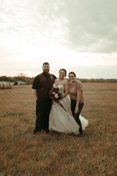 photographer posing with bride and groom