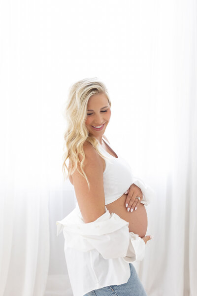 Pregnant woman in studio dressed in white