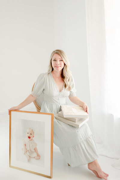 Kristie Lloyd sits in her Franklin studio holding photo albums and wall art