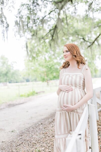 Pregnant woman standing by fence for Maternity portrait session Savannah 