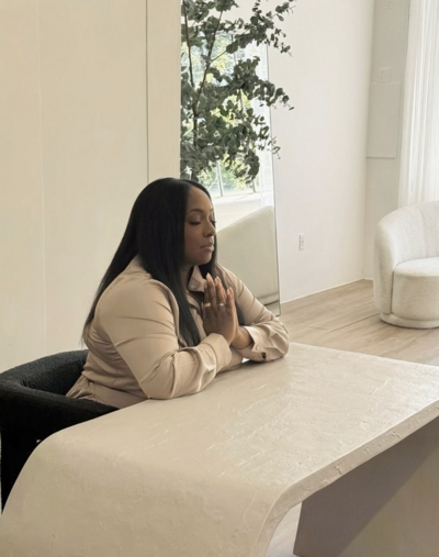 woman sitting at desk with eyes closed and hands in a prayer