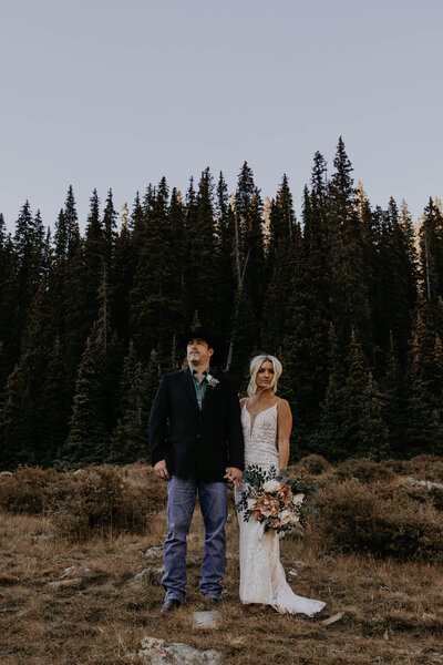 bride and groom kissing infront of red rocks with their dog