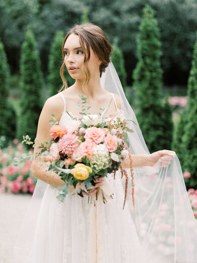 A bride looks away while holding her flowers after getting ready with Indianapolis makeup artists Something Blue