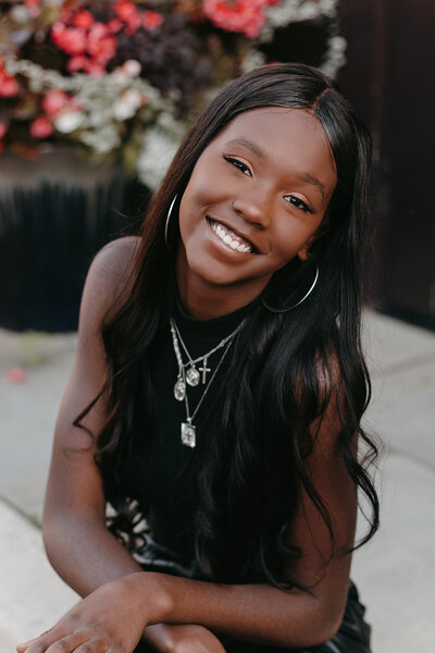 Senior girl in a black top and necklaces posing with her arms crossed