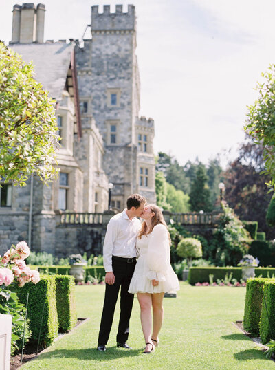 Gorgeous couple kissing opposite majestic  Hatley Castle in Victoria