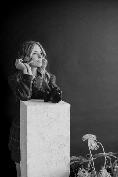 Emily's camera is sitting on a white pedestal. Behind it is Emily playing with her hair, slightly blurred.