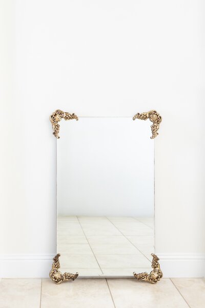 Clear mirror with gold corner decorations on easel stand