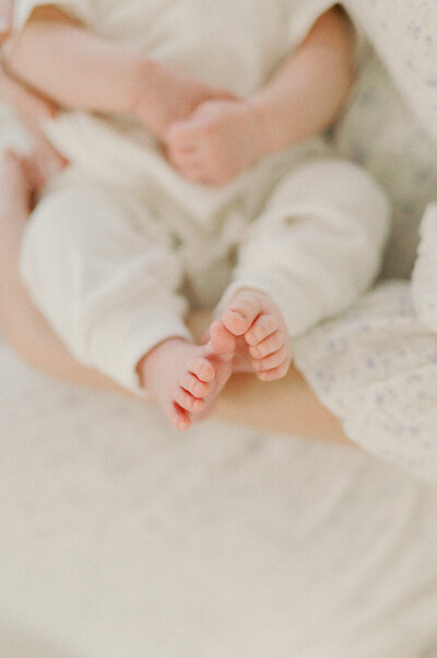 adorable pink newborn baby toes in moms arms