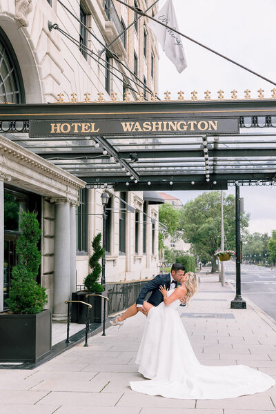 A couple in wedding attire, the bride in a gown and the groom in a blue tux, share a first look inside the Washington Hotel in Washington DC. The photo was taken by Get Ready Photo.