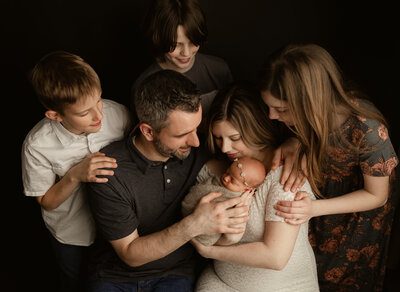 Large family gathered around a newborn baby during an in-studio family and newborn session at Duehr Photography in Maple Grove.